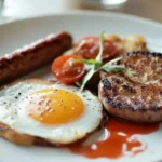 Traditional English breakfast with sausage, egg, grilled tomato, and potato pancake.